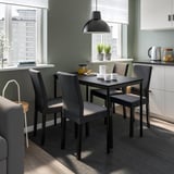 Zona de comedor moderna con cadeiras KÄTTIL e mesa, vistas urbanas, decoración acolledora.