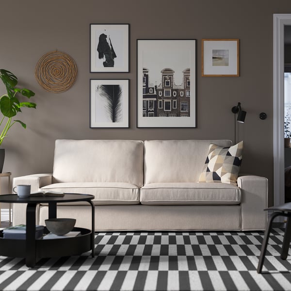 Sala de estar moderna con sofá KIVIK, mesa de café, alfombra a cadros e lámpada de chan.