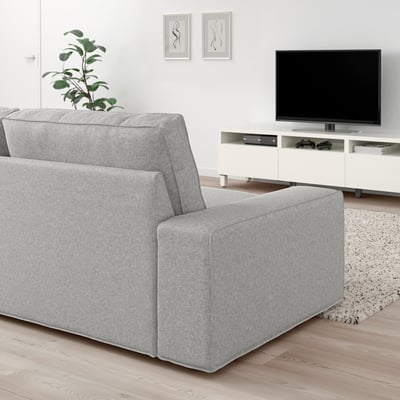 Sala de estar moderna con sofá KIVIK gris, televisión e planta.