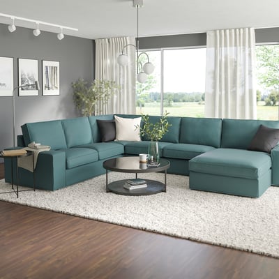 Turquesa KIVIK sectional, mesa de café negra, alfombra branca, grandes fiestras con vista de campo.