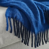 Manta azul con textura fluffy e detalle de franxas.