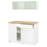 Configuración moderna de cociña branca con mesa de carballo, armario de vidro e caixóns de almacenamento.
