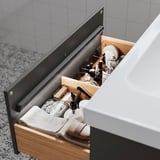 Caixón de baño aberto que mostra artigos de baño ben organizados. A luz suave iluminase automaticamente cando se abre.