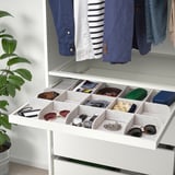 Organizador de caixóns abertos con compartimentos para accesorios, cintos, reloxos e outros pequenos obxectos.