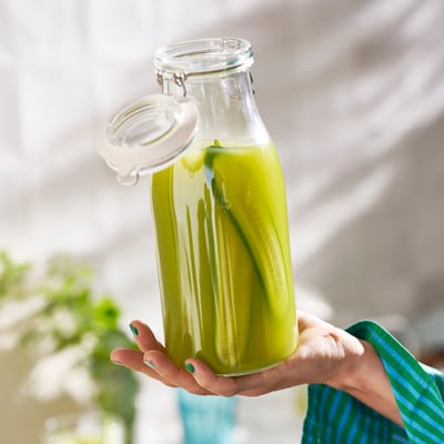 Frasco de vidro transparente con tapa metálica, ideal para o almacenamento de alimentos. Transparente, cilíndrico cun fondo plano.