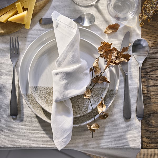 Elegante mesa de vacacións con servilletas de algodón branco, pratos e cubertos.