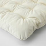 Coxín KUDDARNA en primeiro plano: superficie suave, crema, texturizada con costuras.