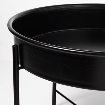 Un elegante soporte de plantas de metal negro cunha base circular e patas de apoio.