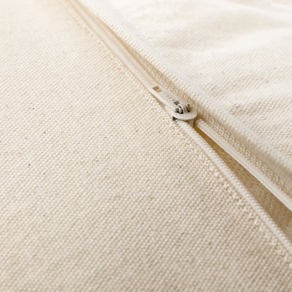 Primeiro plano de cuberta de coxín con cremalleira beige con textura tecida sutil.