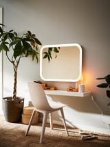 Moderna vaidade branca con espello, cadeira e plantas. Deseño limpo e minimalista.
