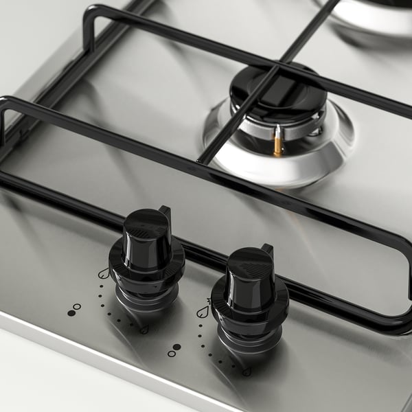 Cociña de gas de aceiro inoxidable con botóns de control negros e cubertas de queimadores metálicos, deseño elegante e moderno.