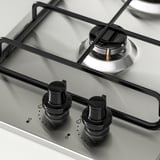 Cociña de gas de aceiro inoxidable con botóns de control negros e cubertas de queimadores metálicos, deseño elegante e moderno.