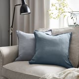 Cadeira moderna con almofada cadrada LAGERPOPPEL azul-gris, acento floral, lámpada elegante, decoración neutra.