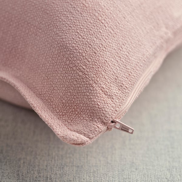 Primeiro plano de coxín rosa suave e texturizado con cremalleira.