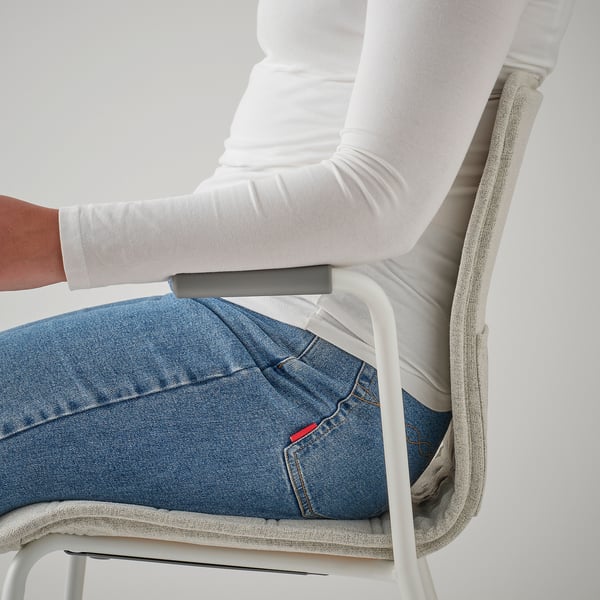 Persoa sentada nunha cadeira de conferencia, mostrando o repouso de brazos e o soporte lumbar das cadeiras.