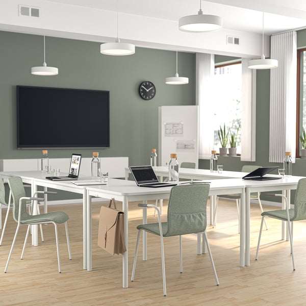 Sala de conferencias moderna con cadeiras LÄKTARE en tecido verde, mesas brancas e pantalla grande. Lixeiro, apilable e cómodo con cubertas extraíbles.
