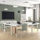 Sala de conferencias moderna con cadeiras LÄKTARE en tecido verde, mesas brancas e pantalla grande. Lixeiro, apilable e cómodo con cubertas extraíbles.