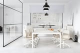Sala de reunións minimalista moderna con cadeiras brancas LÅNGFJÄLL, mesa de vidro, luz colgante negra e particións de vidro.