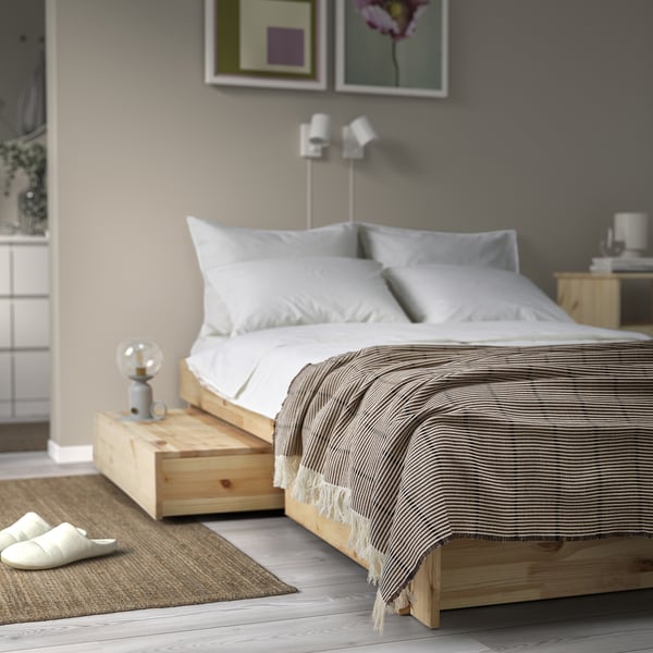 Dormitorio acolledor con LAPPKATTFOT lanzamento sobre cama de madeira, mesas de noite, almofadas brancas, alfombra pequena.