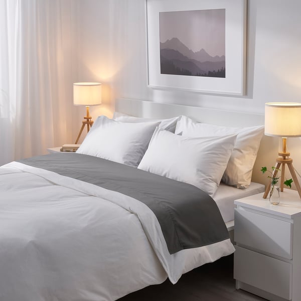 Dormitorio moderno con lámpada de mascotas recicladas LAUTERS sobre mesa de noite branca xunto á cama grande.