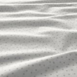 Duvet de algodón suave con pequenos puntos grises espallados en tecido branco, con liñas de costura suaves.
