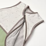 Saco de durmir para bebés suave, de cor neutra con puntos de polka simpáticos, cremalleiro a medio camiño, mostrando costuras de alta calidade e tecido cómodo.