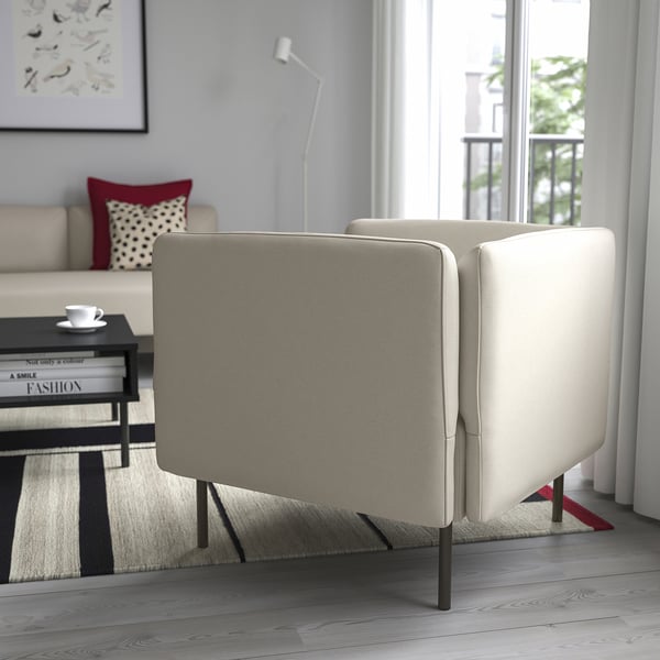 Sala de estar moderna con sofá LILLEHEM, xanela grande, mesa de café negra e almofada vermella. Parede gris con lámpada e arte.