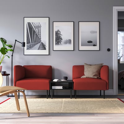 Sala de estar moderna: dous vibrantes sofás modulares vermellos de Lilleham, mesa de café elegante, estampados elegantes e exuberante verde.