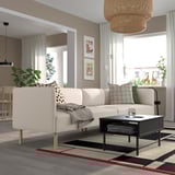 Sala de estar moderna con sofá LILLEHEM, mesa de café negra, alfombra, plantas e gran xanela.
