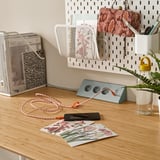 Escritorio organizado con carga de teléfono, planta, papeis e cable USB.