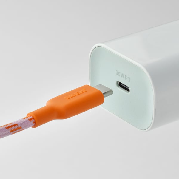 Un cable USB-C laranxa brillante está conectado a un cargador branco.