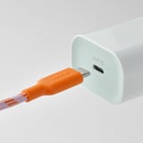Un cable USB-C laranxa brillante está conectado a un cargador branco.