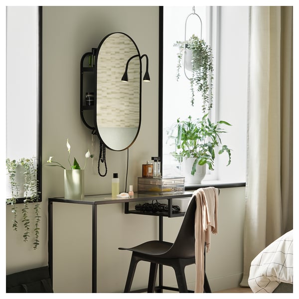 Dormitorio moderno con escritorio LINDBYN negro, espello ovalado, plantas colgantes e cadeira negra.