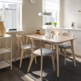 Comedor moderno con mesa e cadeiras de madeira clara LISABO, que ofrece vistas urbanas a través de grandes fiestras.