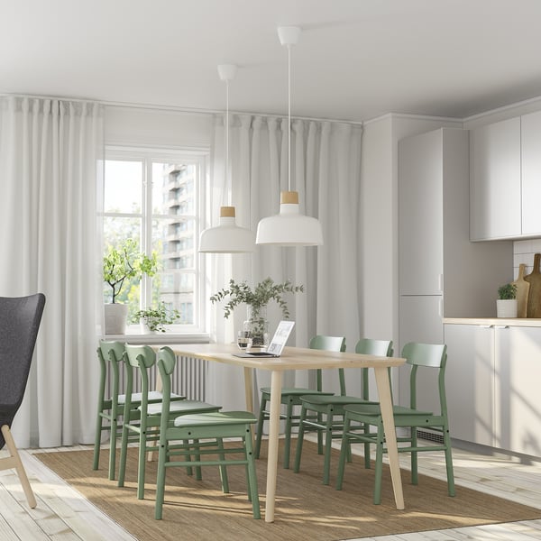 Comedor moderno con mesa LISABO, cadeiras verdes, luces colgantes e gran xanela.