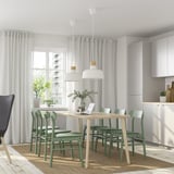 Comedor moderno con mesa LISABO, cadeiras verdes, luces colgantes e gran xanela.