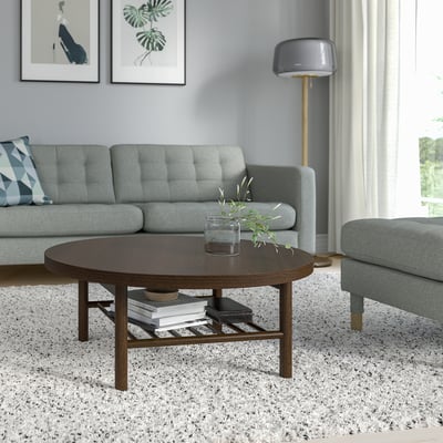 Salón moderno con mesa de café LISTERBY, libros, planta, sofá azul, lámpada, obra de arte.