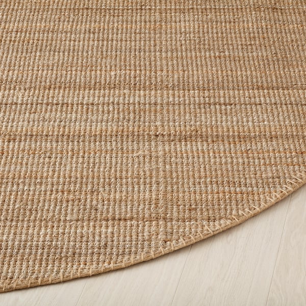 Alfombra redonda rústica, estreitamente tecida con fibras de xute de ton natural, que amosa unha superficie duradeira e texturizada, ideal para decoracións acolledoras e rústicas.