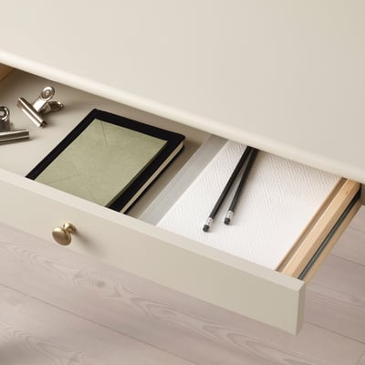 Caixón de escritorio aberto con caderno e material de oficina.
