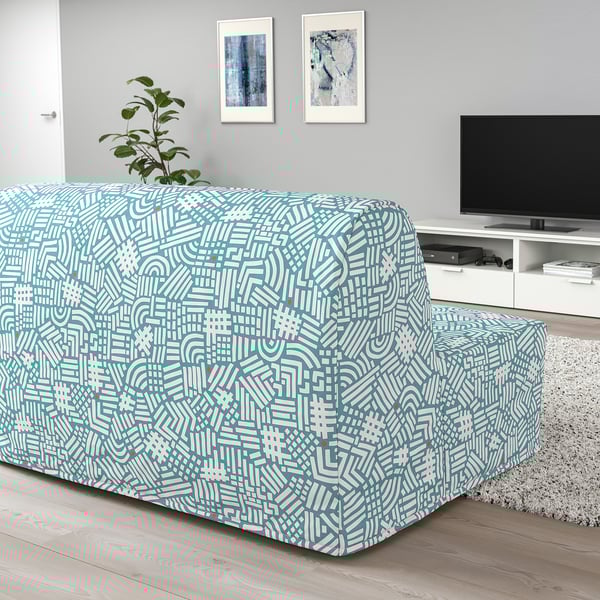 Sofá con patróns azul con ottoman na sala de estar, con deseño xeométrico, consola de televisión, arte e planta.