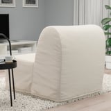Unha moderna cadeira-cama branca LYCKSELE LÖVÅS nun espazo de estar, transformándose dunha cadeira a unha cama única. É unha cuberta de tecido suave e neutro.