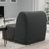 Cadeira-cama gris sobre alfombra, mesa lateral negra con cunca de café.