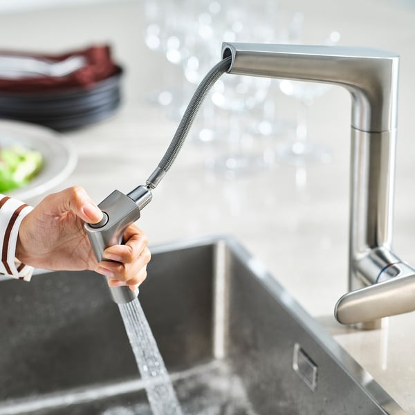 A man sostén as billas MAJSJÖN pulverizador extraíble, a auga flúe del ao lavabo de cociña de aceiro inoxidable.