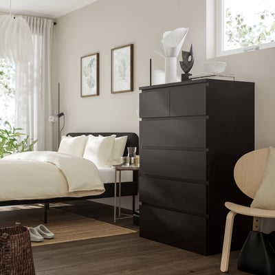 Dormitorio moderno con peito negro MALM, cama e lámpada de noite.