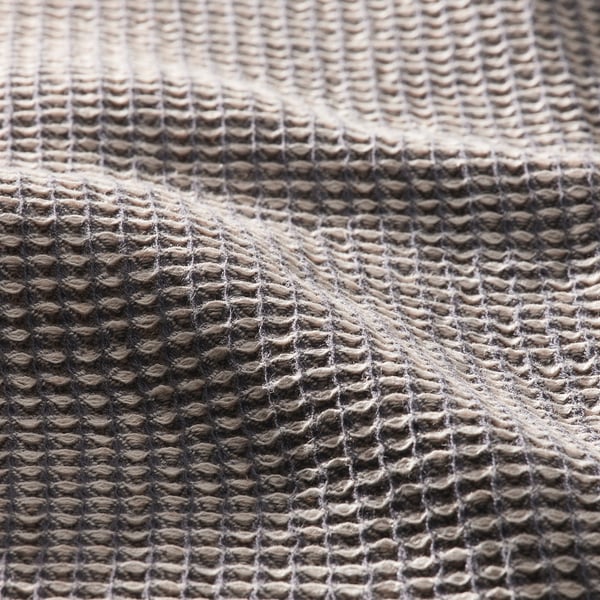 Primeiro plano de mestura de tecidos texturizados, gris claro. Intricado patrón de tecido visible, destacando a calidade e a absorción.