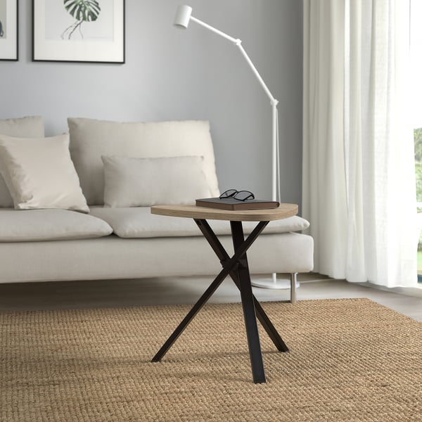 Mesa de lado moderna con parte superior de madeira clara e pernas de metal escuro xunto ao sofá branco.