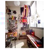 Sala acolledora con chaquetas, ferramentas, taburete, banco e roda de bicicleta.