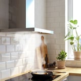 Cociña moderna con backsplash de ladrillo branco e capa de aceiro inoxidable. Utensilios de madeira, plantas e tixola de cociña na mesa.