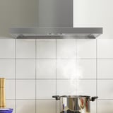 Capa de escape de cociña con luz led sobre a cociña, backsplash de baldosa branca.