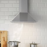 Capa de cociña de aceiro inoxidable contra baldosas brancas con luz led e interruptores rocker, mostrado en acción con potas debaixo.